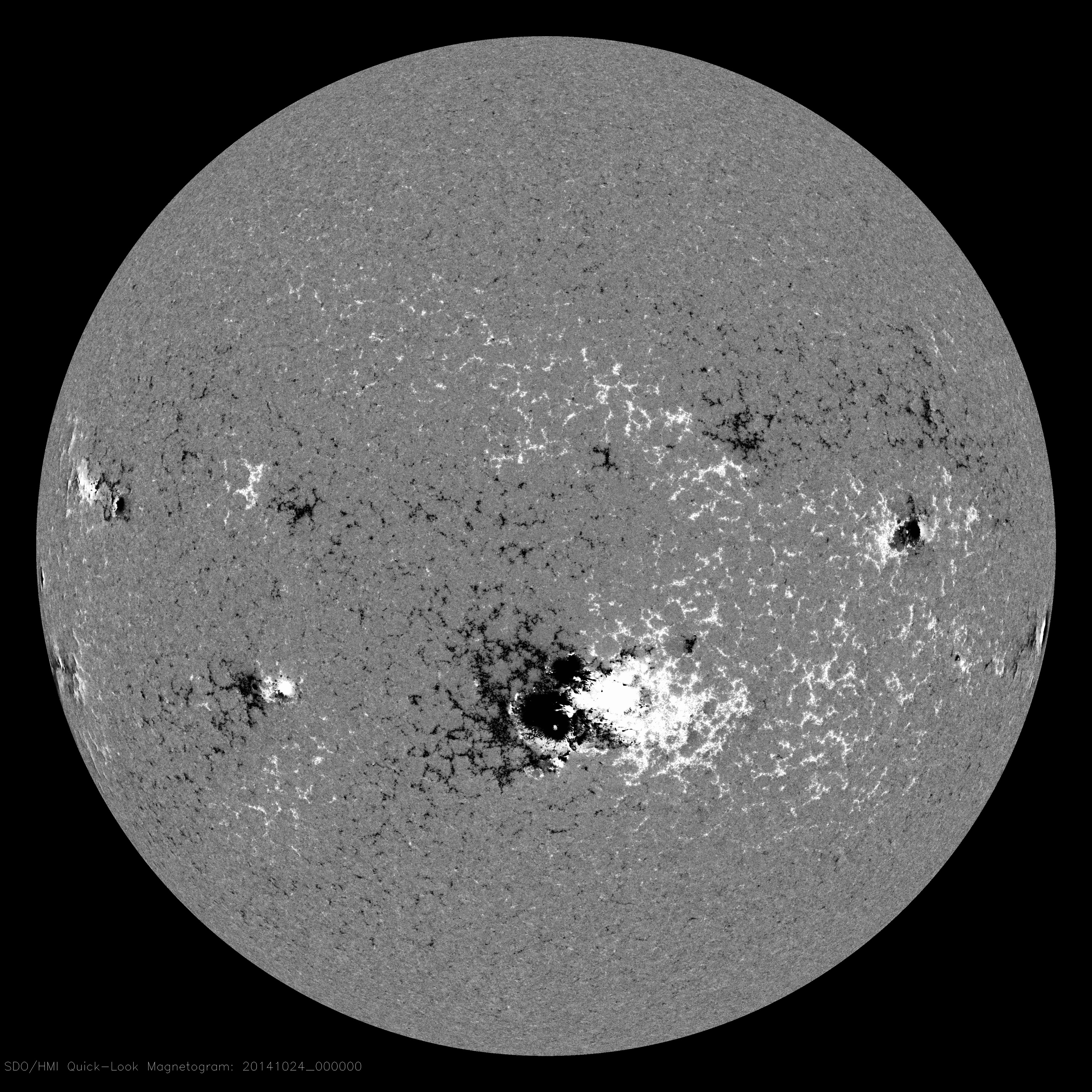Magnetograma del Sol en el mismo momento que la Figura 1 fue tomada (24 de octubre de 2014). Muestra el campo magnético en la fotosfera del Sol, donde el negro y el blanco indican polaridades opuestas. Esta imagen ilustra el concepto de polaridad de las manchas solares presentado en la descripción del proceso de dinamo en el Sol: las componentes de una pareja de manchas solares tienen polaridades opuestas, los dos hemisferios del Sol también tienen polaridades opuestas, y la mancha solar que circula por delante tiene la polaridad de su hemisferio. Fuente: Cortesía de NASA/SDO y los grupos científicos AIA, EVE y HMI. // Credit: Courtesy of NASA/SDO and the AIA, EVE, and HMI science teams.